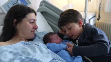 Yeni doğmuş bir bebeğin ilk günü hastane kliniğinde ağabeyi tarafından karşılandı. Bebek, annesi ve kardeşinin yanında yattı. Otantik gerçek hayat yürek ısıtan aile sahnesi, anne bakımı.