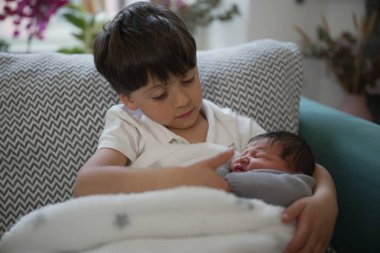 Genç bir çocuk yeni doğan kardeşini şefkatle kucağına alır. Huzurlu ve samimi bir aile ortamında birbirlerine sevgi ve şefkat gösterirler..