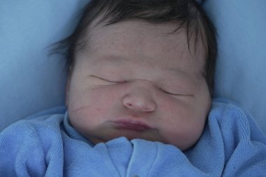 Hastanede yeni doğmuş bir bebeğin huzur içinde uyuması sakin ve besleyici bir ortamda yeni bir hayatın masumiyetini ve huzurunu vurguluyor.