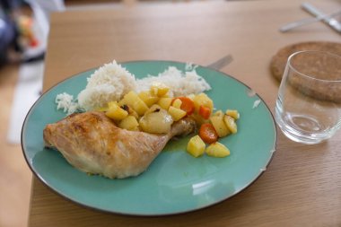 Pirinç ve sebzeli tavuk budu ve yeşil tabakta servis edilen lezzetli bir yemek. Aperatif yemek ev yapımı konforlu yemekleri ön plana çıkarıyor. Besleyici bir aile yemeği için mükemmel.