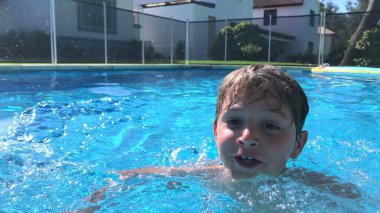 Çocuk havuzda yüzüyor.
