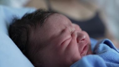 Yeni doğan bebek ağlamasına yakın çekim, mavi battaniyeye sarılı, ham duyguları ve hayatın ilk ifadelerini yakalamak, bebeklik, incinebilirlik ve yeni başlangıçların güzelliği için idealdir.