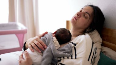 Yorgun Anne, Yeni Doğmuş ile Yatakta Göğsünde Yatıyor, Yaşamın İlk Haftası Kucaklıyor. Sevecen Anaç Sahne. Yorgun hisseden bir kadın, kestiriyor.