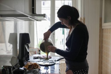 Ocağın üstünde gülen surat kalıbına krep hamuru döken bir kadın eğlenceli ve lezzetli bir kahvaltı hazırlıyor. Sahne rahat bir mutfağa ve ev yapımı yemeklere vurgu yapıyor..