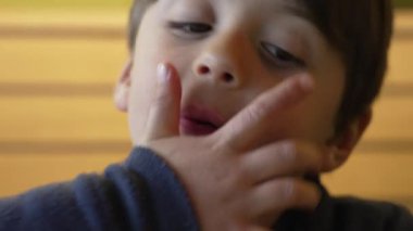 Çocuk şevkle sulu bir çizburgerden büyük bir ısırık alıyor, keyifli ve neşeli bir yüz ifadesi sergiliyor ve sıradan bir lokantada yemeğinin tadını çıkarıyor.