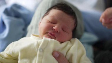 Yumuşak bir gülümseme ile yeni doğmuş bebek, yumuşak bir battaniyenin üzerinde mutlu bir şekilde uyuyor. Huzurlu ve huzurlu ifade, yeni doğmuş bir bebeğin masumiyetini ve saflığını vurgular.