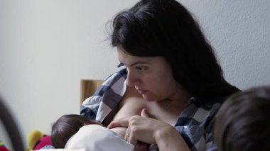 Anne yeni doğmuş bebeğini şefkatle emziriyor. Huzurlu ve samimi bir yuva ortamında bir bağ kurup onu besliyor.