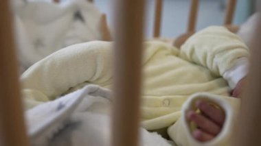 Sarı tulumlu sevimli bir bebek tahta bir beşikte huzur içinde uyuyor. Erken çocukluğun sükunetini ve saflığını yakalıyor. Aile ve sağlık hizmetleri için ideal.