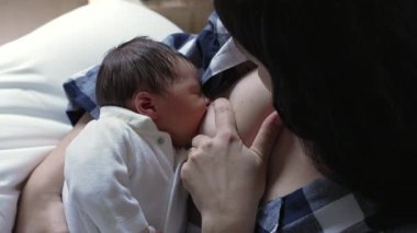 Yeni doğan bebek huzur içinde emziriyor, annesine yakın duruyor, şefkatli bağı vurguluyor ve sakin, samimi bir evde bakım yapıyor.