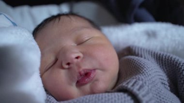 Yeni doğmuş bebek rahat bir battaniyenin içinde uyur, yumuşak, örülü bir kazak giyer, hayattaki ilk anların sükunetini ve huzurunu yakalar.