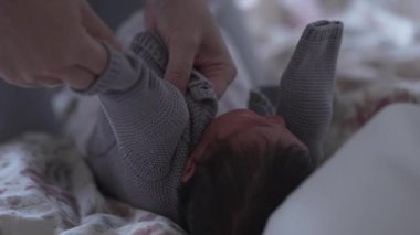 Yeni doğan ebeveynler rahat gri bir kazak giyip bebeklere sunulan hassas bakım ve sıcaklığa odaklanarak yeni doğanları rahat ve korunmuş tutmanın önemini vurguluyorlar.