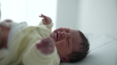 Hemşire hastane rutini sırasında bebek bezi değiştirirken bebek rahatsız oluyor. Yeni doğan bakımının temel unsurları, bebek hijyeni için gerekli hassas ve dikkatli bakımı vurguluyor