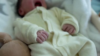 Bebek beşikte dinleniyor, yumuşak, beyaz bir battaniyeyle örtülmüş, hafifçe hareket ediyor, çocukluklarının sükunetini ve konforunu gösteriyor, ve yeni doğanlara ilk günlerinde verilen hassas bakımı gösteriyor.