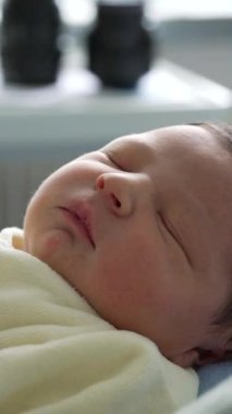 Yeni doğmuş bebek, yumuşak bir battaniyenin içinde huzurlu bir şekilde uyuyor. Erken yaşların sakinliğini ve narin özelliklerini yakalıyor.