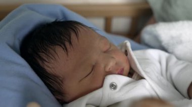 Koyu renk saçlı yeni doğmuş bebek beyaz bir kıyafetle uyur. Eski hayatın masumiyetini ve sakinliğini yakalar. Sükunet, saflık ve yeni aile üyelerinin temaları vurgulandı