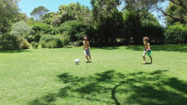 Children playing soccer outside at home lawn
