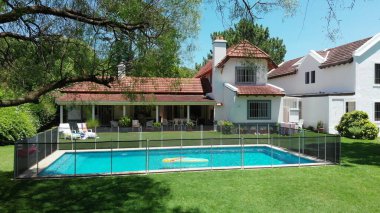 Suburban home exterior revealing pool and lawn