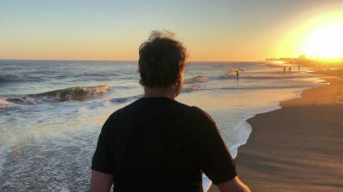 retired man walking at the beach shore during sunset