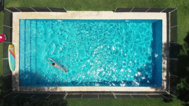Vertical aerial perspective of child swimming inside pool