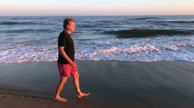 Senior man walking at the beach during sunset