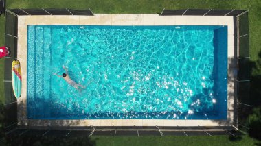Vertical aerial perspective of child swimming inside pool