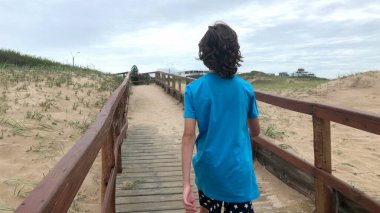 Çocuk sahil yolunda yürüyor.