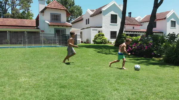 Children playing soccer outside at home lawn