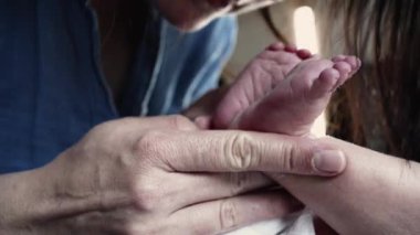 Sevgi dolu bir anne, yeni doğmuş bebeğinin küçük ayağını nazikçe öper, şefkatli bir anı yakalar ve aralarındaki derin bağı yakalar. saf sevgi ve annelik.