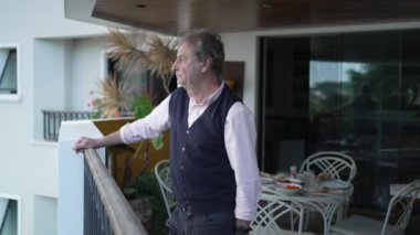 Ciddi İfade Veren, Büyük ve Güzel Ağaçlarla çevrili Apartman Balkonundan Görünümü Gözlemleyen Üst Düzey Üst Düzey Üst Düzey Adam Orta Çekimi