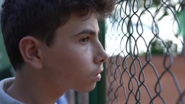 Metal çitlere bakan bir çocuğun portresi 