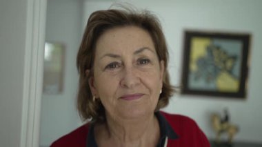 Evde gülümseyen yaşlı bir kadının portresi.