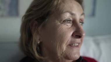 Evde gülümseyen yaşlı bir kadının portresi.