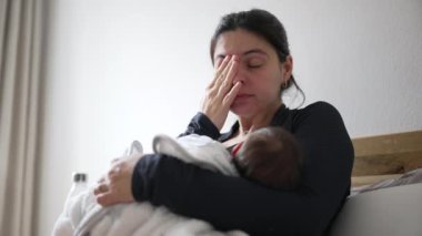 Annem yorgun hissederken bebek beşiği yapıyor. Eller yüzleri kaplar, erken anneliğin zorluklarını yakalar, yorgunluk ve yeni doğmuş bir bebeği yetiştirmek için gereken hassas bakım