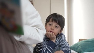 Küçük çocuk, büyükannesi masal okurken ona yaslanıyor. Yakınlık ve bağlılık, aile bağlarının sıcaklığını vurgulamak ve ortak okuma anlarının neşesini paylaşmak.