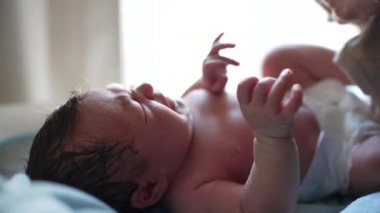 Yeni doğmuş bebek uzanmış, sadece bebek bezi giyiyor, yumuşak ışıkla aydınlatılıyor, hayatın ilk anları, narin cilt ve yüz hatlarını gösteriyor, huzurlu ve huzurlu bir sahne, masumiyeti vurguluyor.