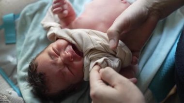 Anne yeni doğan bebeğin giyinmesine yardım ediyor, bebeğin eline hassas dokunuşlar, ilgi ve ilgi gösteriyor, ilk anlarda bağ kuruyor ve büyütüyor, şefkat ve sevgi besliyor.