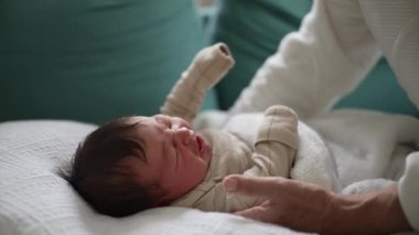 Yeni doğmuş bir bebeğin ağlaması, kanepenin üzerinde yumuşak bir battaniyeye uzanması, yanında şefkatli bir büyükanneyle, erken çocukluk ve aile etkileşiminin anlarını yakalaması.