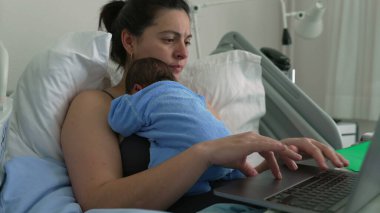 Anne yeni doğmuş bebekle hastane yatağında, dizüstü bilgisayarla çalışıyor, uzaktan kumanda ve ebeveynliği karıştırıyor, sağlık ve teknoloji, doğum sonrası bakım, aile bağlantısı