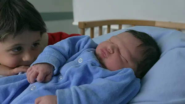 stock image Heartwarming scene of a young boy gazing at his newborn sibling in a blue outfit, highlighting the tender family bond, love, and excitement of welcoming a new baby into the family