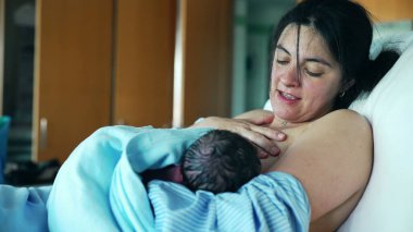 Yeni anne, doğumdan sonra ilk beslenmeyi ve annelik bakımını vurgulayarak yeni doğan bebeğini hastanede emziriyor.