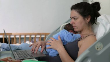 Hastanede yeni anne dizüstü bilgisayarda çalışıyor, mavi tulumlu yeni doğmuş bebek göğüs, çoklu görev, annelik bakımı, denge işi ve bebek, erken annelik, bağlanma zamanı, yeni ebeveyn