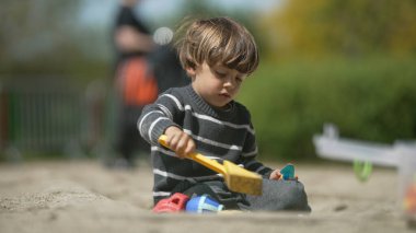Renkli Oyuncaklarla Kum havuzunda oynayan, Yeşiller Parkı 'nda Yaratıcılığı Keşfeden Konsantre Yürüyen Çocuk
