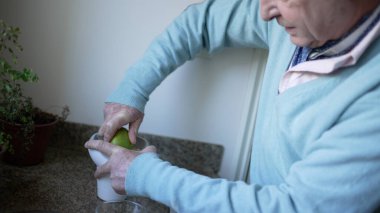 Son sınıf öğrencisi mutfakta taze meyve suyu için limon sıkıyor, sağlıklı yaşam tarzına odaklanıyor.
