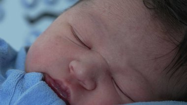 Yeni doğmuş bebek makro yakından uykuya dalıyor. Huzurlu bir şekilde uyumak, bir bebeğin ilk günlerindeki narin özelliklerini ve sakinliğini vurgulamak.