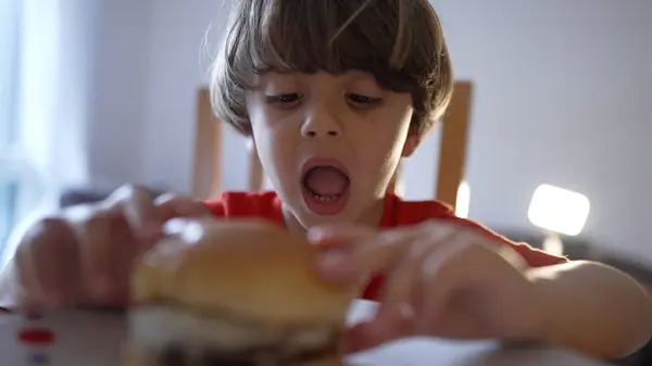 stock image Excited Young Boy About to Take a Bite of a Delicious Cheeseburger at Home