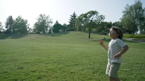 stock image Young Child Enthusiastically Chasing After a Toy Plane in a Lush Green Park