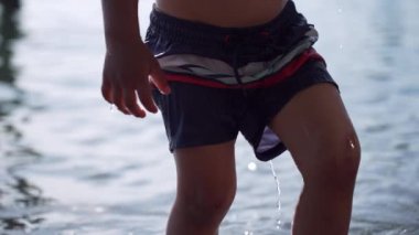 Oğlanın Bacakları Kristal Gölü 'nden çıkıp Yaz Sıcak Gününde Taş Dolu Plaja doğru