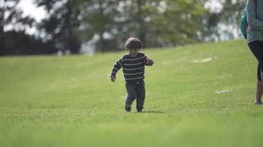 Çizgili Süveterli Gülümseyen Çocuk Yeşil Arazide Güneşli bir günde Kameraya doğru koşar