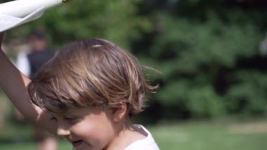 Neşeli Çocuk elinde oyuncak planörle koşar, fırlatmak için heyecanlanır ve diğer insanların arasında Sevimli Park Günü 'nde yükselişini izler.