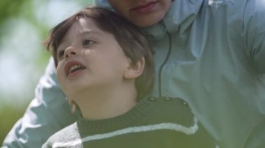Küçük çocuk parkta piknik yaparken annesinin kucağında eğleniyor.